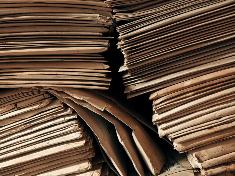 Deep stacks of aged paper and folders, hundreds of sheets seen edge on.